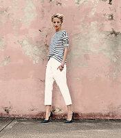 a young blonde woman wearing a stripped shirt, white trousers and snakeskin shoes