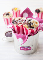 Blueberry and Apple muffins in silver tin sprinkled with icing sugar and raspberry sauce on side
