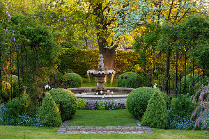 Springbrunnen zwischen Gehölzen und Frühlingsblumen