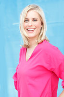 Junge blonde Frau in pinkfarbener Bluse