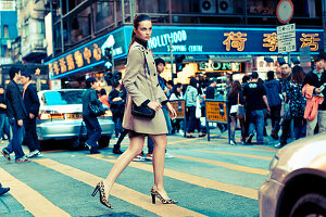 Junger Frau in camelfarbenem Mantel auf der Straße