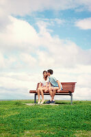 A young couple sitting outside on a bench