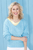 A young blonde woman wearing a blue jumper over a yellow top