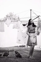 A young woman hanging out washing wearing a summer dress (black-and-white shot)
