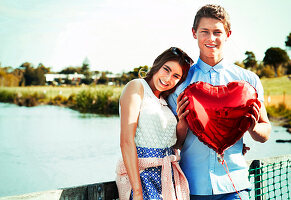 A young couple with a red, heart-shaped balloon