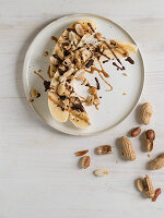 Halved bananas with peanuts, peanut butter and chocolate