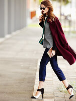 A young woman wearing a dark-red coat, blue trouser and high heels