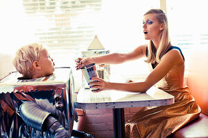 Blonde Frau und kleiner Junge als 'Roboter' verkleidet im Restaurant