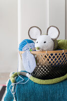 A crocheted mouse in a basket of wool