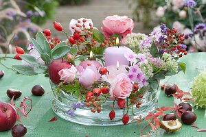 Roses, Rose Hips, Perennials, Sage And Candles As A Table Arrangement