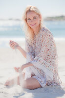 A blonde woman on a beach wearing a patterned tunic