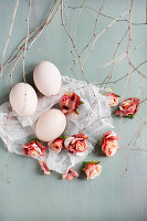 Roses and white eggs on muslin amongst twigs