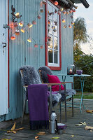 DIY fairy lights made from paper baking cases, a plaid and sheepskins on garden chairs