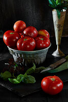 Still life with fresh beefsteak tomatoes and basil on black background