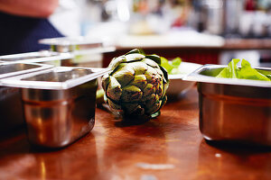 Artichokes between metal containers in a kitchen