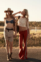 Two friends wearing summer outfits on a country road