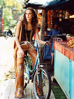 A brunette woman with a bike in front of a market stall