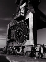 A blonde woman standing in front of an industrial machine (black-and-white shot)
