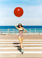 A brunette woman with a balloon wearing a bathing suit