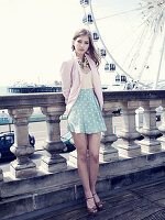 Young woman wearing polka-dot skirt and blazer standing on bridge