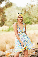 A young woman outside wearing a turban and a floral patterned summer dress