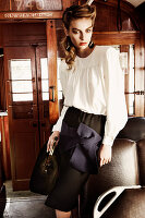 Junge Frau in eleganter, weißer Bluse und schwarzem Rock im Zug