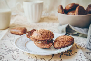 Chocolate glazed soft gingerbread cookies on a white plate, bowl of cookies, and milk