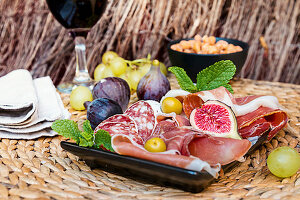 Italian antipasti plate with ham, salami, cheeses, olives, figs and wine