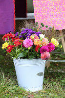 Brightly coloured bouquet of autumn flowers in metal bucket