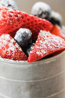 Frische Erdbeeren und Blaubeeren mit Puderzucker in einem Metallbecher (Close Up)
