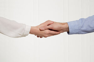 A man and a woman shaking hands (body language: loose handshake)