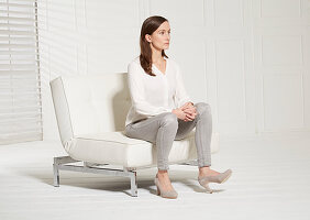 A woman sitting on a chair lifting a toe (body language: rejection)