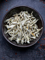 Dried anchovies in a black bowl (seen from above)