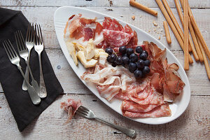 Assorted cured meats on a plate with breadsticks