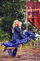 Blonde Frau in luftigem, blauem Kleid und blau-kariertem Mantel