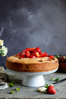 Strawberry cake on the cakestand, topped with fresh strawberries