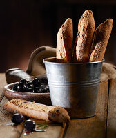 Olive baguettes in a metal bucket with black olives