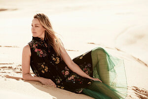 Junge Frau im Kleid mit floralem Print und grünen, transparenten Rock in der Wüste