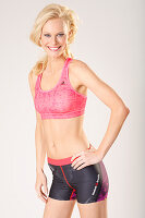 A young blonde woman wearing a pink sports bra and shorts