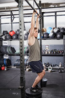 A young man performing a burpee jumping pull-up on a pull-up bar