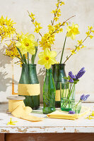 Spring arrangement of forsythia, narcissus and hyacinths in bottles and glasses