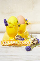 Yellow egg cups decorated for Easter with forsythia and hyacinth florets