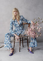 A blonde woman wearing a blue-and-white trouser suit holding a spray of magnolias