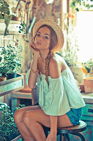 A young woman wearing a a straw hat, an off-the-shoulder blouse and shorts