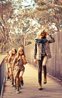 A young woman on a bridge with children wearing uniform