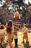 Junge Frau mit Kindern in Uniform auf der Wiese spielend
