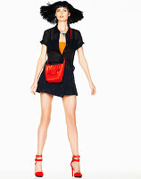 A black-haired woman wearing an orange top and a black dress