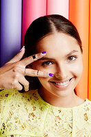A young woman showing purple finger nails in front of her eyes