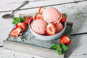 Strawberry yoghurt ice cream with fresh strawberries in a bowl