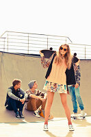 A group of young people wearing fashionable clothing skating in a skatepark